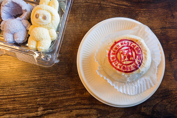 Overhead view of a round Asian pastry, with the name of the brand — Tân Hưng — stamped in red. Next to it, a container of Labubu-shaped desserts.